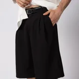 Bermuda sastrera gris de corte baggy, con pinzas al frente y diseño holgado que se extiende por debajo de la rodilla.