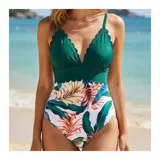 Malla enteriza bicolor de diseño combinado, con parte superior lisa en color negro de escote en V pronunciado con bordes ondulados, y parte inferior con estampado botánico de hojas verdes y flores rosadas sobre fondo negro. Cuenta con tirantes finos regulables.