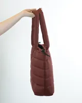 Bolso tipo tote bag acolchado color bordó, con asas de hombro tubulares y logo estampado en el frente.