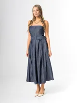 Vestido midi strapless de denim azul, con escote recto, espalda elastizada y falda amplia con pliegues. Incluye un cinto del mismo material con hebilla.