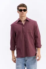 Camisa rústica de manga larga color gris oscuro, con cuello clásico, cierre frontal con botones y un bolsillo aplicado en el pecho.