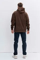 Buzo con capucha tipo canguro confeccionado en tela de corduroy color marrón. Presenta cordones blancos en contraste, bolsillo frontal tipo canguro y logo bordado sutil en el pecho.
