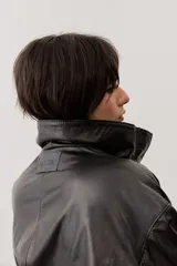 Chaqueta de cuero color negro, de corte oversize, con cierre frontal y solapas.