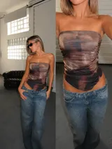 Top strapless de satén con diseño estampado abstracto en tonos marrones y negros. Presenta un corte asimétrico en el ruedo y frunces laterales.