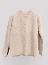 Cárdigan de punto trenzado color beige, con cuello redondo y cierre frontal de botones a tono. Presenta mangas largas con puños acanalados y un diseño clásico de textura tejida.