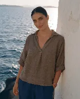 Blusa de lino color blanco, con cuello camisero y escote en V profundo, mangas 3/4 y corte holgado.