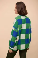 Buzo oversized de punto texturizado, con diseño a cuadros en tonos de verde, azul y blanco. Tiene cuello redondo y puños acanalados.