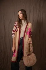 Cartera marrón de piel sintética con textura de pelo, forma redondeada y doble asa corta.