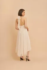 Vestido midi de fiesta color crudo, con cuello halter, cuerpo drapeado y falda de microtul plisado.