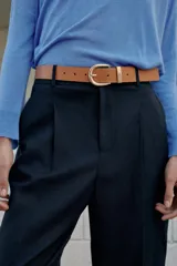 Pantalón tobillero azul marino de tiro medio, con pinzas delanteras, bolsillos frontales, falsos bolsillos con solapa en la espalda y cierre frontal con cremallera, botón y gancho. Incluye cinturón de cuero sintético tostado con hebilla metálica dorada.