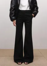 Pantalón de vestir negro estilo flare de tiro medio, con trabillas y cierre frontal con botón, gancho y cremallera.