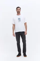 Remera de manga corta color beige, con cuello redondo y estampa gráfica central con motivos botánicos y texto.