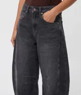 Pantalón baggy balloon de jean negro con efecto acid wash, cintura mediana con trabillas y bolsillos funcionales. Presenta recortes laterales que acompañan la modelaje redondeada de las piernas.
