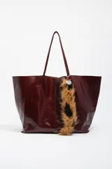 Asa para cartera de pelo sintético con diseño animal print en tonos marrón y negro. Cuenta con enganches metálicos y un dije en forma de corazón con el logo grabado.