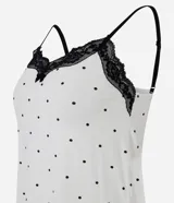 Conjunto de pijama compuesto por una musculosa de breteles finos ajustables con detalle de encaje negro en el escote y un short con cintura elástica. Ambas prendas presentan un estampado de lunares negros sobre fondo blanco.