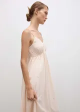 Vestido largo de corte evasé en color beige, confeccionado en tejido fluido con textura. Presenta escote en pico, tirantes finos y delicados detalles de abalorios bordados en toda la prenda.