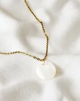 Collar dorado con dije circular de nácar.