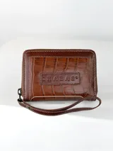 Mini billetera de cuero con textura efecto cocodrilo y cierre perimetral. Presenta un parche central con el logo de la marca grabado.