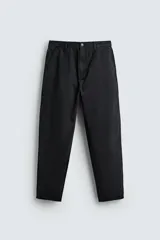 Pantalón de corte carrot fit confeccionado en algodón con estructura diagonal y efecto lavado. Presenta bolsillos frontales con bolsillo cerillero, bolsillos traseros de plastrón, acabados irregulares y cierre frontal con cremallera y botón.