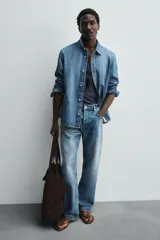 Bolso tipo shopper de gran tamaño confeccionado en piel con acabado de serraje. Presenta un diseño minimalista con costuras visibles, compartimento principal amplio y dos asas de hombro integradas.