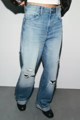 Jeans de tiro medio con corte baggy, cinco bolsillos y bajo con dobladillo. Cierre frontal con cremallera y botón metálico.