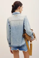 Camisa de denim color celeste con lavado claro, de manga larga, con bolsillos frontales con solapa y cierre de botones metálicos.