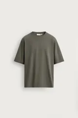 Camiseta boxy fit color verde militar con efecto lavado, confeccionada en tejido compacto de algodón, con cuello redondo y manga corta.