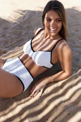 Conjunto de bikini blanco con ribetes negros, corpiño con aros y bombacha de tiro alto.