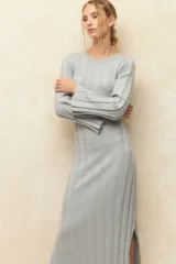 Vestido midi de punto acanalado en color gris, con mangas largas acampanadas y aberturas laterales en el ruedo. Presenta un diseño ajustado al cuerpo.