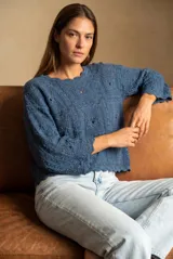 Sweater de tejido de punto calado en color azul, con diseño de textura geométrica, cuello redondo y mangas tres cuartos con terminaciones onduladas.