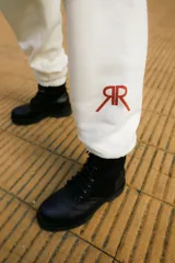 Jogger de frisa color off white, con cintura y puños elásticos, bolsillos laterales y logo bordado en la parte frontal.