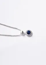 Collar de plata 925 con cadena tipo bismarck y dije circular estilo Lady Di, con una piedra central de zirconia azul rodeada por pequeñas zirconias blancas.