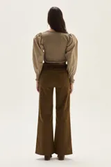 Top de calce ajustado color marrón, con escote cuadrado y mangas largas abullonadas de tela lisa. Los puños de las mangas son elastizados.