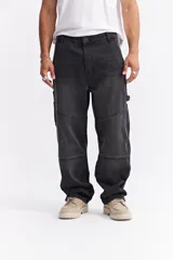 Jean estilo carpenter de corte relajado y tiro medio, confeccionado en denim color negro lavado. Presenta costuras reforzadas en las rodillas y bolsillos laterales funcionales inspirados en ropa de trabajo.