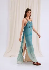 Vestido largo fluido de gasa translúcida con diseño degradado en tonos azul agua y celeste. Presenta escote recto, breteles finos, espalda baja y aberturas laterales pronunciadas.