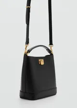 Bolso de mano tipo bucket color negro, con estructura rígida y asa corta superior. Presenta un cierre metálico frontal en color dorado y detalles de herrajes a juego.