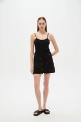 Short pollera negro de algodón y viscosa, de diseño holgado, con bordados decorativos y detalles metálicos en la cintura.