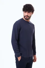 Buzo de manga larga con textura tipo waffle, cuello redondo y corte holgado.