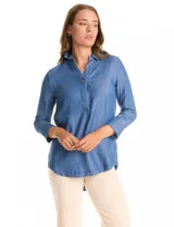 Blusa de lyocell color azul con efecto denim, cuello camisero con solapa y escote en V con cierre de un botón. Presenta mangas tres cuartos con terminación doblada y ruedo redondeado.
