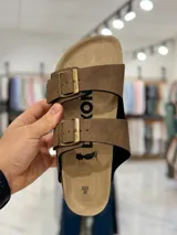Sandalias marrones de dos tiras con hebillas metálicas doradas y plantilla anatómica.