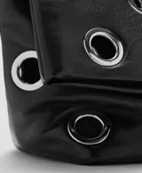 Bolso tipo tote de color negro, confeccionado en poliuretano, con diseño de ojales metálicos plateados distribuidos por toda la superficie y asas largas para llevar al hombro.
