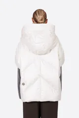 Campera tipo capa acolchada, con capucha y cierre frontal de botones a presión. El exterior es de nylon color beige claro metalizado y el forro de la capucha es verde militar.