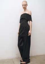 Vestido corto de fiesta en tejido satinado negro, con diseño entallado y escote palabra de honor con solapa vuelta. Presenta apliques decorativos brillantes distribuidos por toda la prenda y cierre de cremallera en la parte posterior.