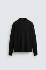 Polo de punto de manga larga con cuello solapa y cierre frontal de botones. Presenta un diseño de corte regular con aberturas laterales en el bajo.