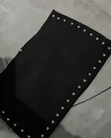Minifalda negra de gamuza con detalle de tachas metálicas plateadas a lo largo de los bordes laterales.