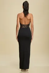 Vestido largo de fiesta con diseño entallado, cuello halter y cuerpo superior confeccionado en encaje negro con forro color nude. Presenta una falda larga de color negro con detalle fruncido en la cintura.