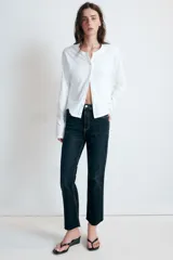 Jeans de tiro alto con cinco bolsillos, diseño cropped flare y bajo sin costuras. Cuenta con cierre frontal de cremallera y botón metálico.