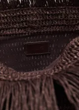Bolso de mano tipo sobre color marrón oscuro, tejido en fibra natural con flecos. Interior forrado.