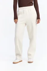 Pantalón de jogging color crudo, con cintura elástica, corte recto y costuras verticales decorativas que recorren el frente de las piernas.