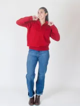 Buzo de punto color gris con cuello alto y cierre frontal parcial. Presenta puños y ruedo acanalados, con un pequeño logo bordado en el pecho.